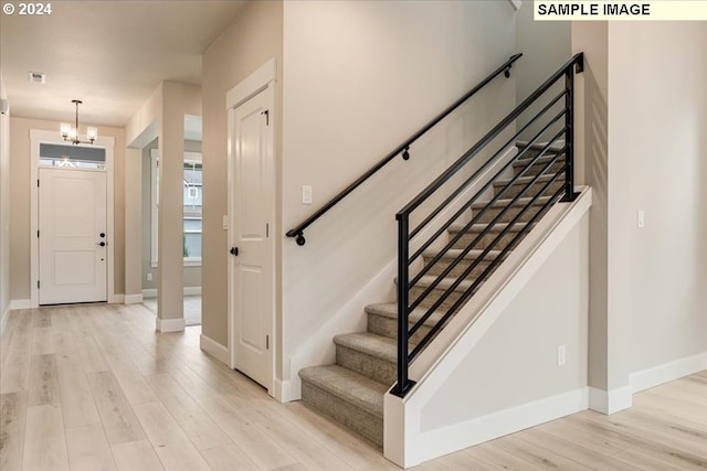 foyer entrance featuring light hardwood / wood-style floors and a notable chandelier