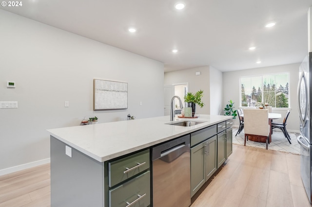 kitchen with sink, stainless steel appliances, light hardwood / wood-style floors, and a center island with sink