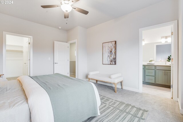 carpeted bedroom featuring connected bathroom, a walk in closet, and ceiling fan