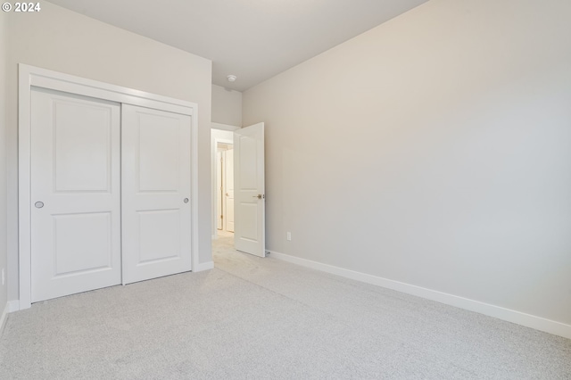 unfurnished bedroom featuring light colored carpet and a closet