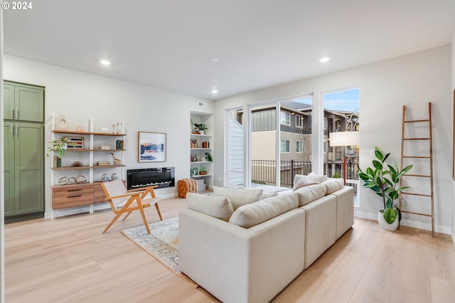 living room featuring light wood-type flooring and built in shelves