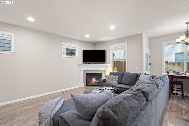 living room with a notable chandelier, a wealth of natural light, and light hardwood / wood-style flooring