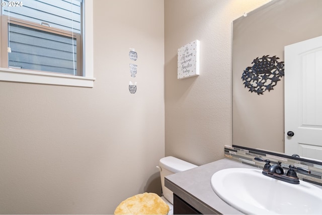 bathroom featuring vanity, toilet, and decorative backsplash