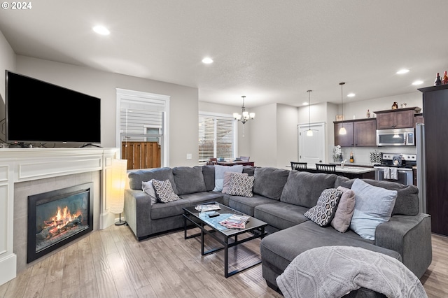 living room featuring a tile fireplace, light hardwood / wood-style floors, and an inviting chandelier