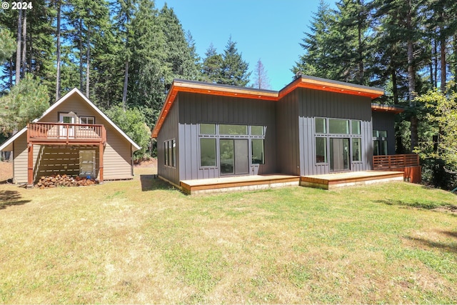 back of property featuring a deck and a lawn