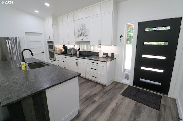 kitchen with stainless steel double oven, white cabinetry, sink, and dark wood-type flooring