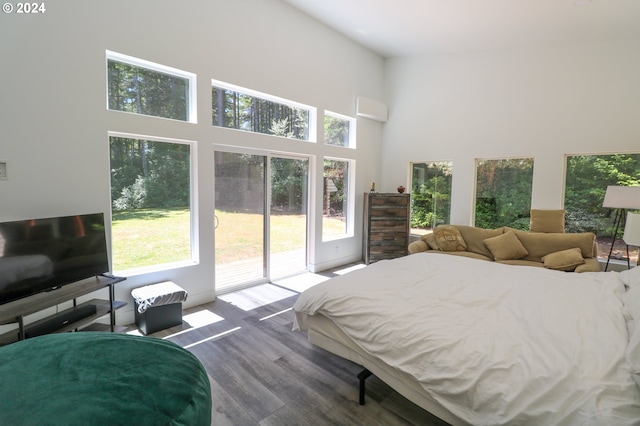 bedroom featuring access to outside, a high ceiling, and wood-type flooring