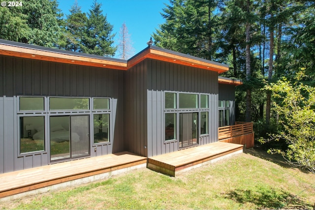 back of property featuring a lawn and a wooden deck