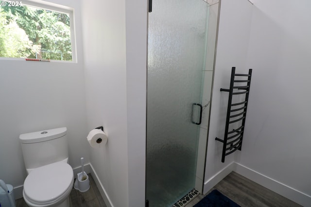 bathroom featuring a shower with door, hardwood / wood-style floors, and toilet