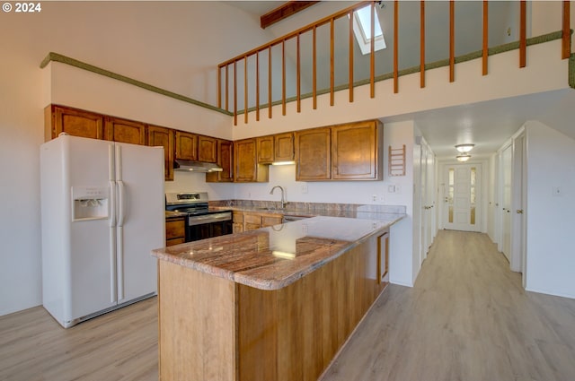 kitchen featuring a towering ceiling, light hardwood / wood-style floors, white fridge with ice dispenser, and stainless steel range with electric stovetop