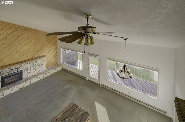 unfurnished living room with baseboard heating, wooden walls, a textured ceiling, and lofted ceiling