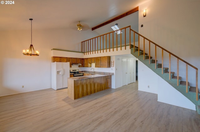 kitchen featuring stainless steel electric stove, sink, light hardwood / wood-style flooring, high vaulted ceiling, and white fridge with ice dispenser