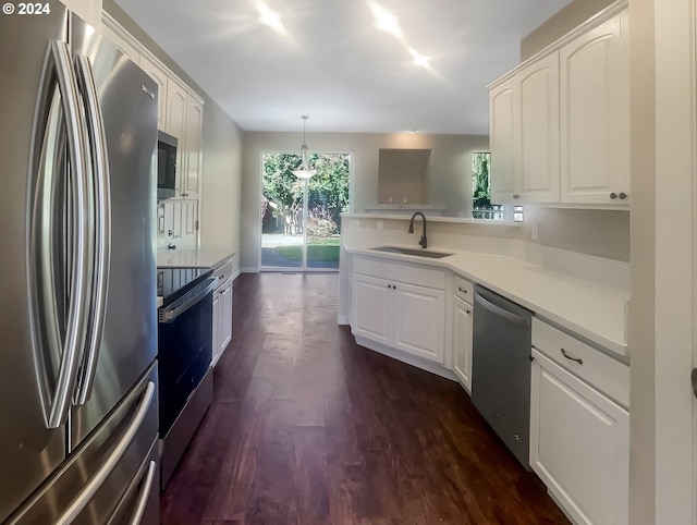 kitchen with stainless steel appliances, dark wood-type flooring, sink, kitchen peninsula, and hanging light fixtures