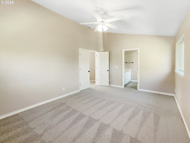 unfurnished bedroom with light colored carpet, vaulted ceiling, connected bathroom, and ceiling fan