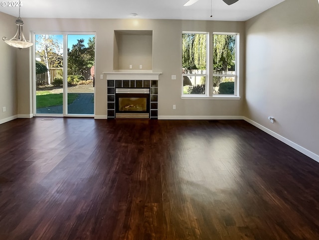 unfurnished living room with a fireplace, ceiling fan, and dark wood-type flooring