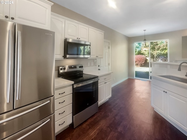 kitchen featuring stainless steel appliances, dark wood-type flooring, sink, pendant lighting, and white cabinetry