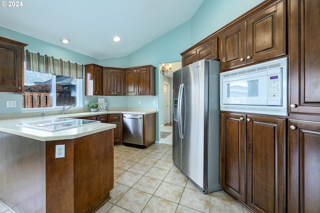 kitchen with sink, stainless steel appliances, kitchen peninsula, lofted ceiling, and light tile patterned floors