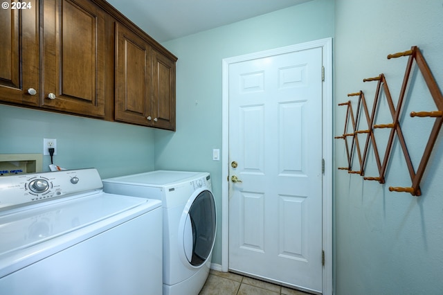 clothes washing area featuring washer and clothes dryer, cabinets, and light tile patterned floors