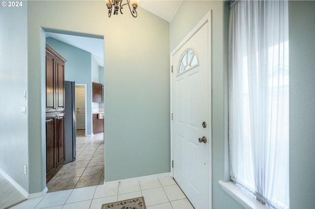 entrance foyer with lofted ceiling, light tile patterned flooring, and an inviting chandelier