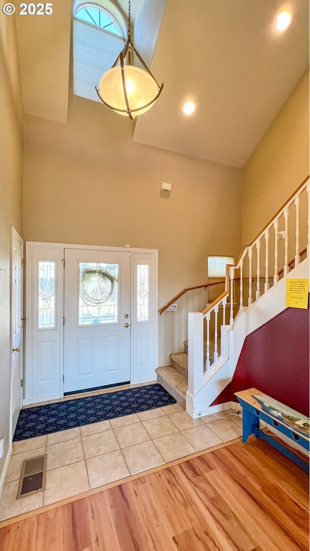 tiled foyer entrance featuring a towering ceiling, stairs, visible vents, and recessed lighting