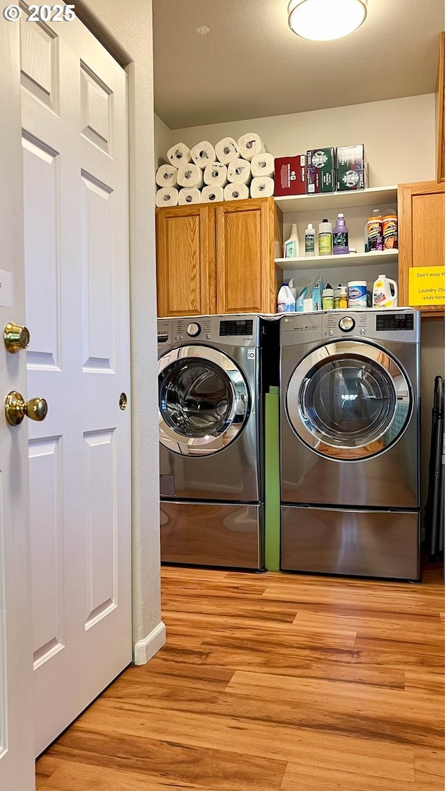 laundry area featuring cabinet space, washing machine and dryer, and light wood-style floors