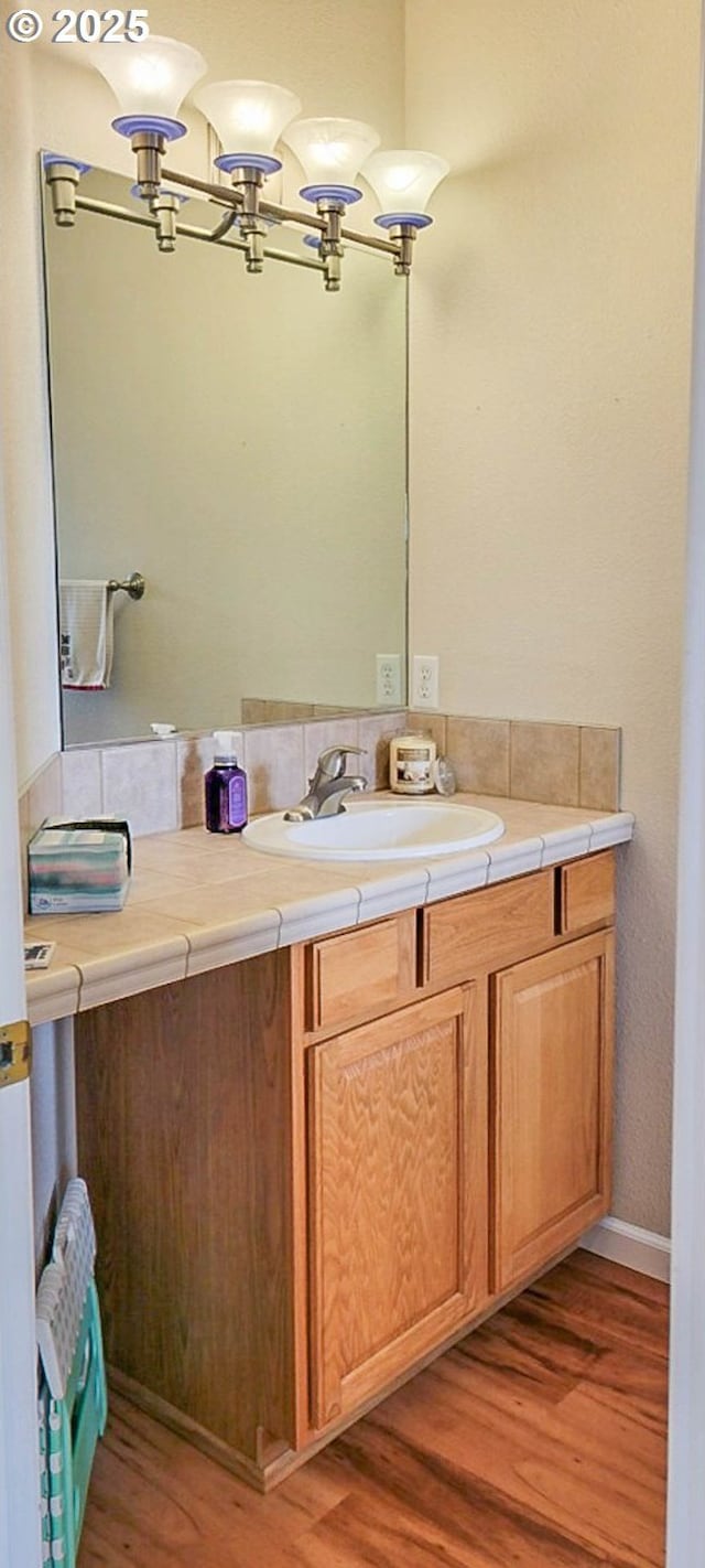 bathroom featuring wood finished floors, vanity, and a notable chandelier