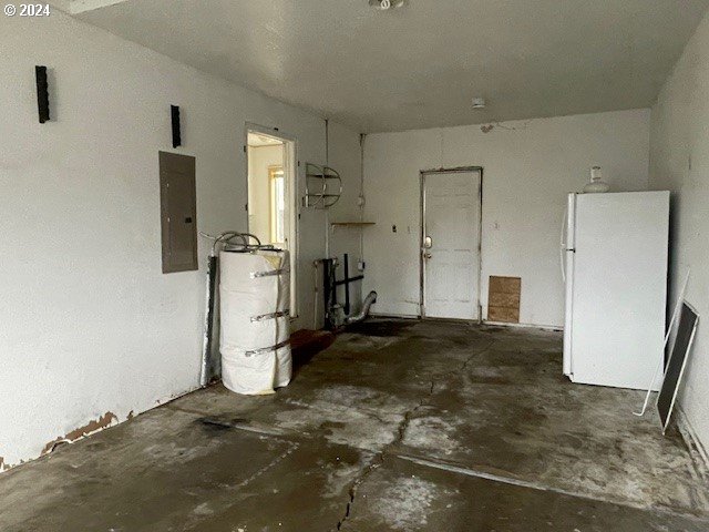 170 NE Exchange Ave, Roseburg, OR 97470 - garage featuring freestanding refrigerator, electric panel, and secured water heater