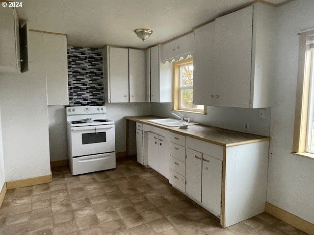 170 NE Exchange Ave, Roseburg, OR 97470 - kitchen featuring electric stove, a sink, white cabinets, light countertops, and baseboards