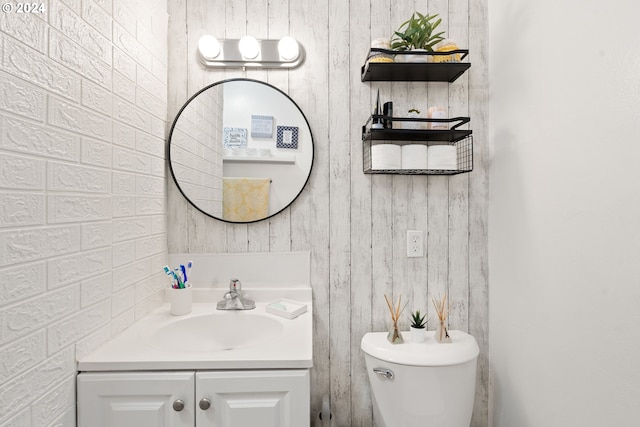 bathroom featuring wooden walls, vanity, and toilet