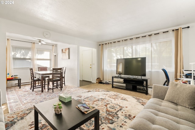 carpeted living room with a textured ceiling, a baseboard heating unit, and ceiling fan