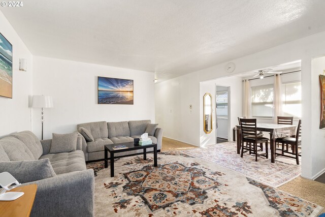 carpeted living room with ceiling fan and a textured ceiling