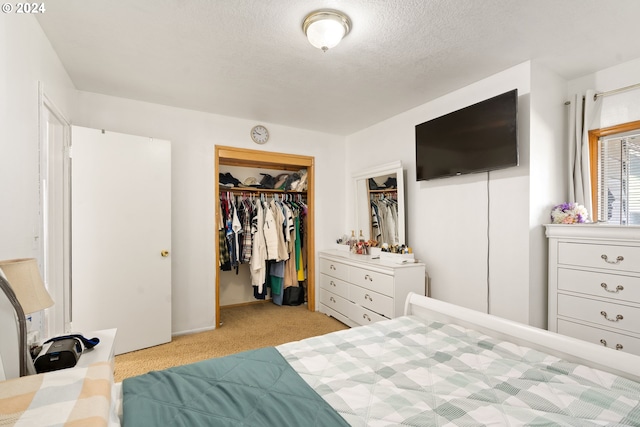 carpeted bedroom with a textured ceiling, a closet, and a walk in closet