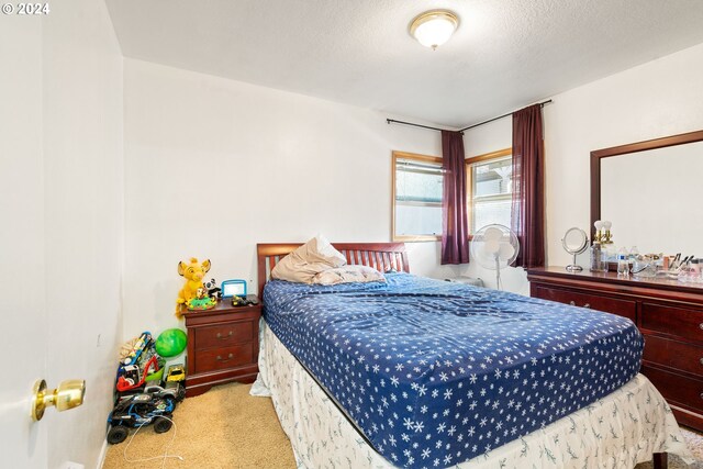 bedroom with a textured ceiling and light carpet