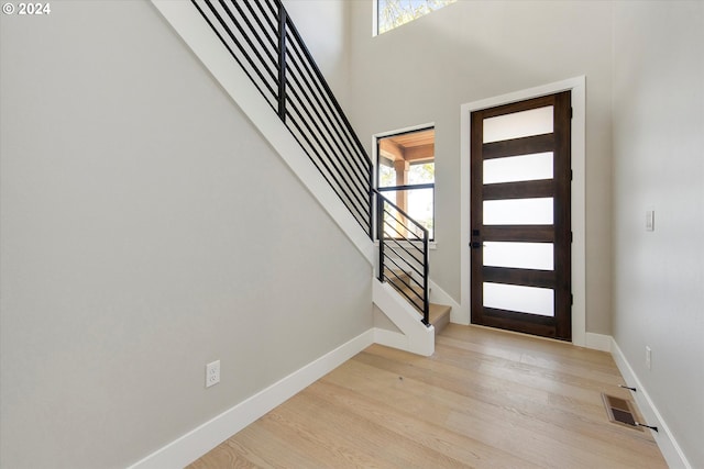 foyer with a towering ceiling and light hardwood / wood-style flooring