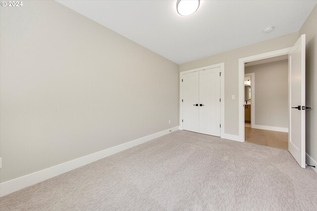 unfurnished bedroom featuring a closet and light carpet