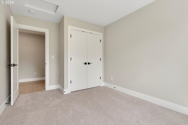 unfurnished bedroom with light colored carpet and a closet