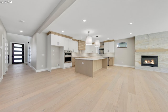 kitchen featuring pendant lighting, white cabinetry, a center island, and light wood-type flooring