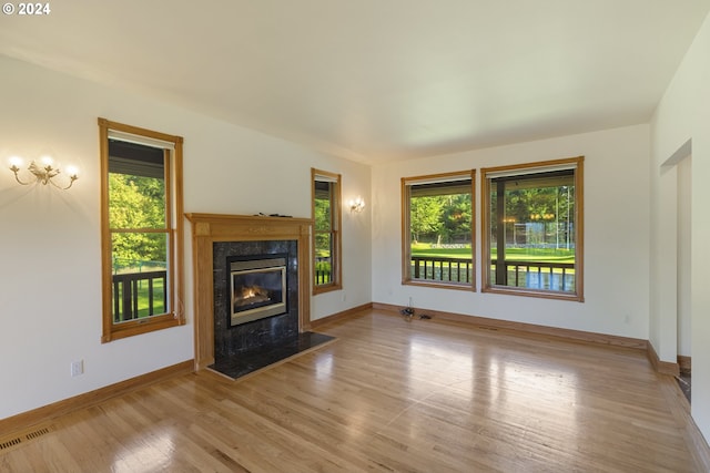 unfurnished living room with light hardwood / wood-style floors, a premium fireplace, and plenty of natural light