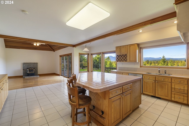 kitchen with a healthy amount of sunlight, a center island, light hardwood / wood-style flooring, and tile countertops