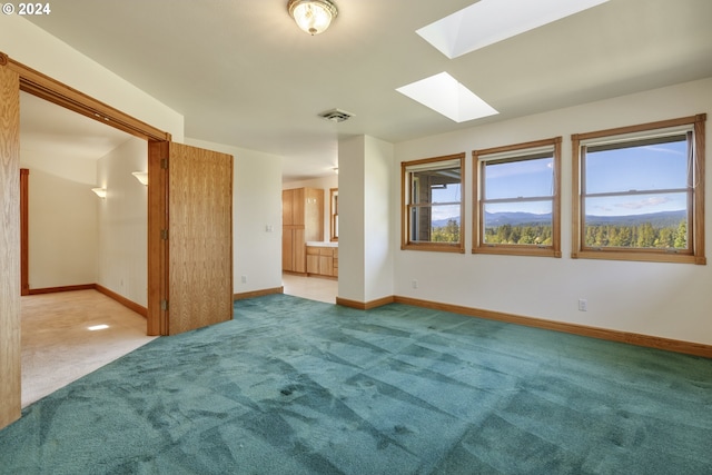 carpeted empty room featuring a skylight