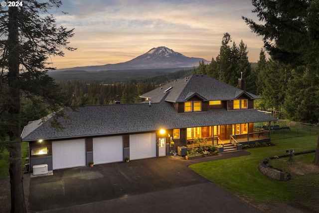 view of front of house featuring a mountain view, a garage, central AC, a porch, and a lawn