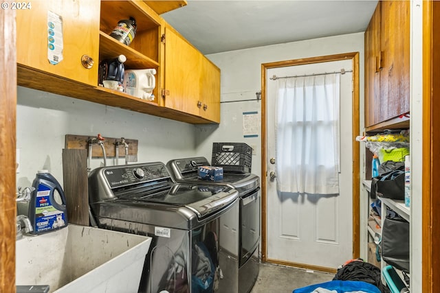 clothes washing area featuring washing machine and dryer, sink, and cabinets