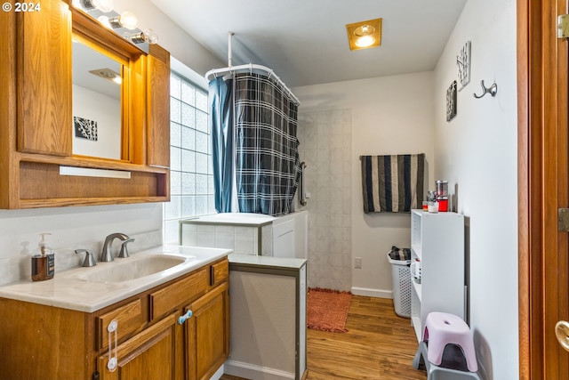 bathroom featuring wood-type flooring, vanity, and tiled shower