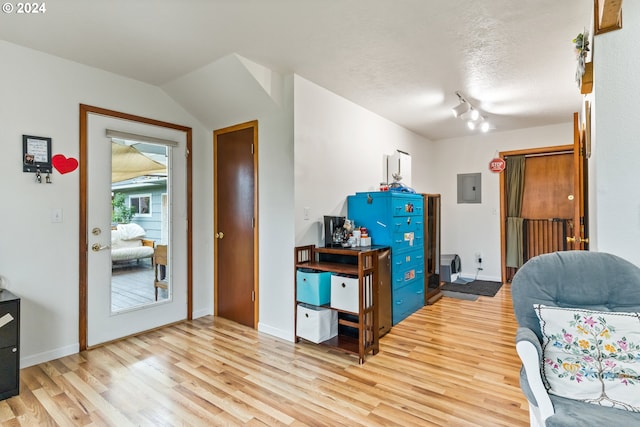 foyer entrance featuring electric panel, light hardwood / wood-style flooring, a textured ceiling, and lofted ceiling