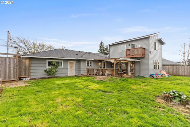 back of property with a balcony, a wooden deck, and a lawn