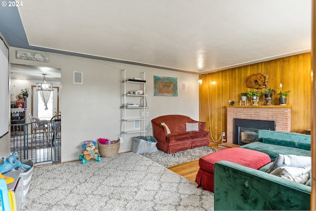 living room with a brick fireplace, wooden walls, crown molding, and hardwood / wood-style floors