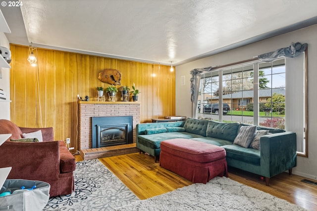 living room featuring hardwood / wood-style flooring, a fireplace, and wooden walls