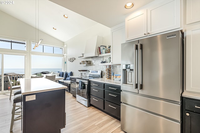 kitchen featuring appliances with stainless steel finishes, a breakfast bar, pendant lighting, white cabinetry, and a water view