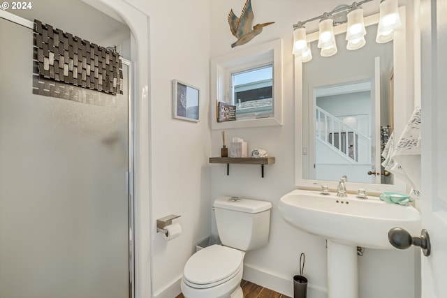 bathroom featuring a shower with shower door and toilet