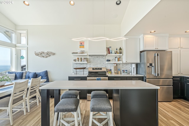 kitchen featuring a breakfast bar, a center island, white cabinets, stainless steel appliances, and backsplash